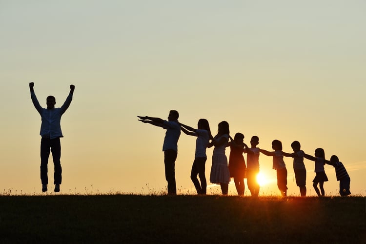 People silhouettes on summer sunset meadow making progress to success