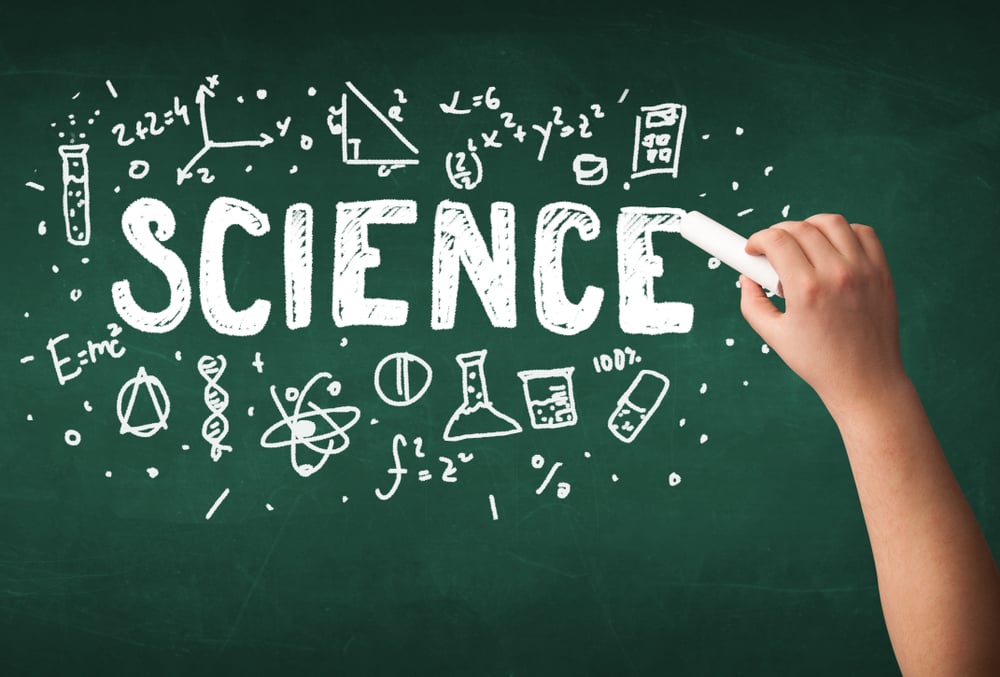 A teacher writing science, drawing chemistry elements on clean green chalkboard by hand
